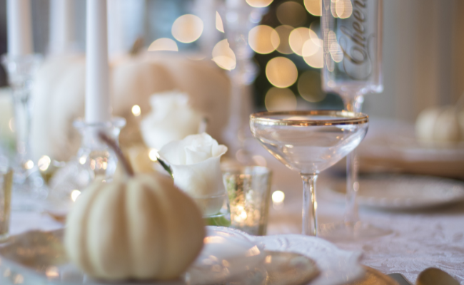 A white pumpkin on a plate, a cocktail in a clear glass coup etched with a gold rim. Blurry lights in the background